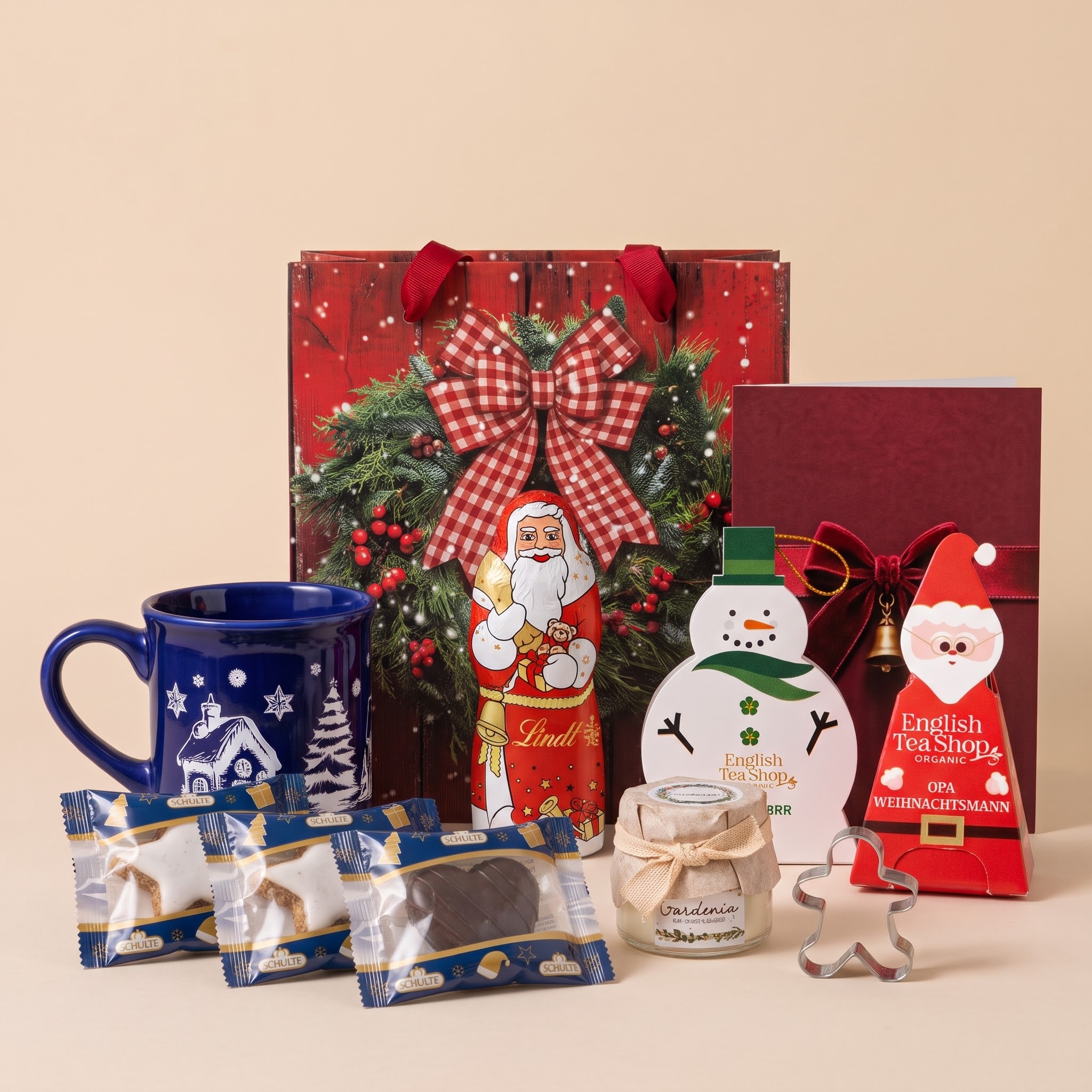 Festliche rote Geschenktüte mit Schleife, weihnachtlichen Leckereien und Grußkarte